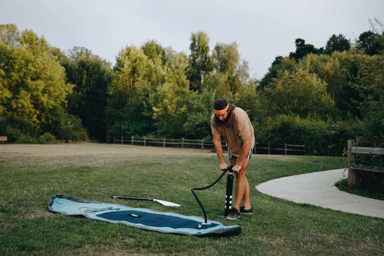 A person working a pump beside an inflatable board