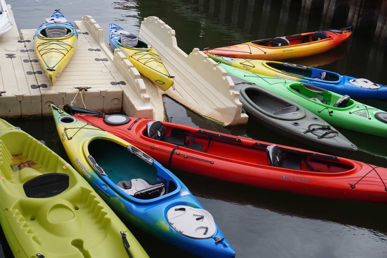 Colourful kayaks lined up along a waterfront dock