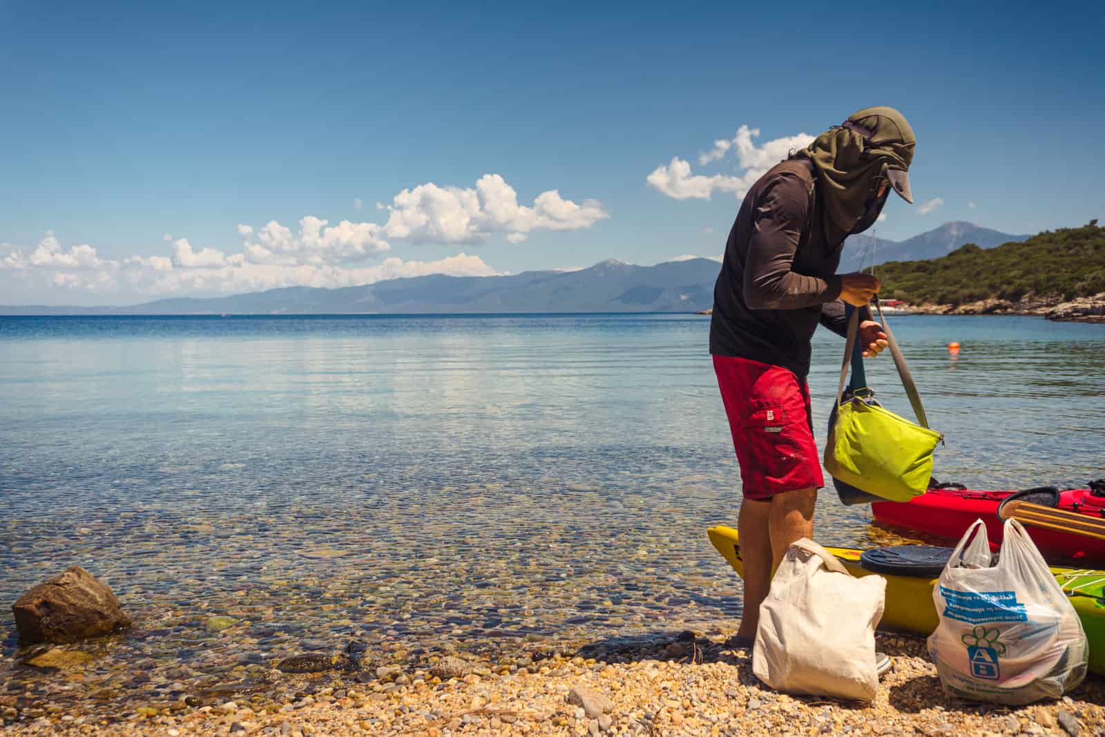 Paddling gear packed into a dry bag on a stony shoreline